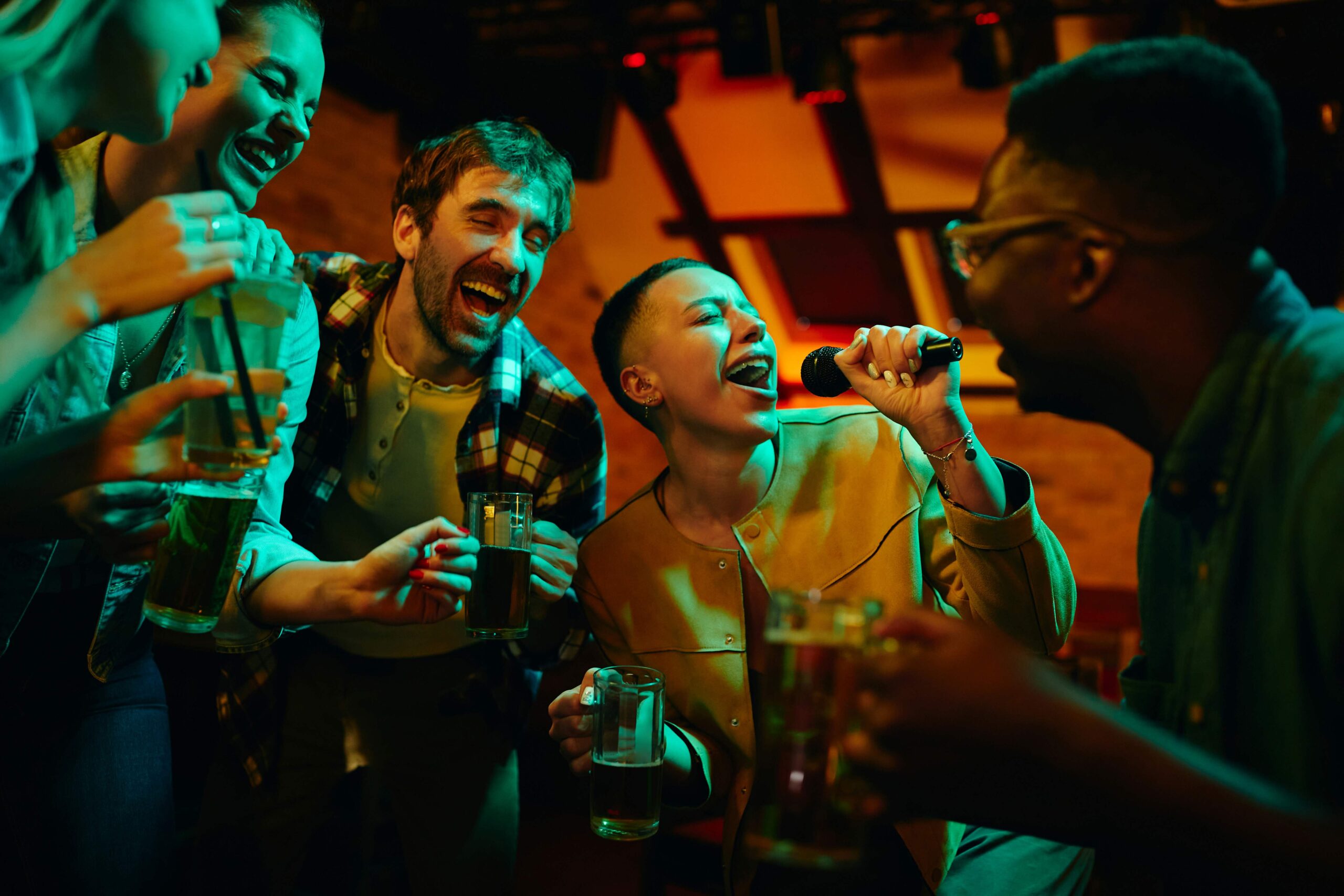 Happy African American woman signing karaoke and having fun with her friends in a bar at night.